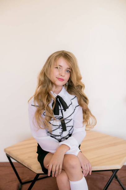 Cute girl with long blond curly hair in school fashion clothes. School fashion in vintage elite style. - Photo, image