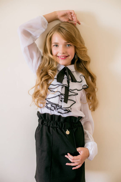 Cute girl with long blond curly hair in school fashion clothes. School fashion in vintage elite style. - Foto, imagen