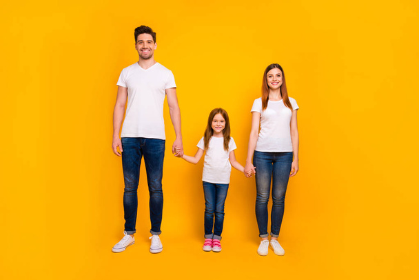 Full length body size view of three nice-looking attractive charming stylish trendy cheerful person holding hands spending weekend isolated over bright vivid shine yellow background - Foto, imagen