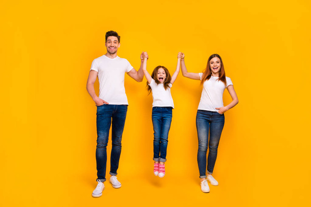 Full length body size view of three nice attractive lovely stylish cheerful cheery carefree person mommy daddy swinging girl having fun life isolated over bright vivid shine yellow background - Photo, Image
