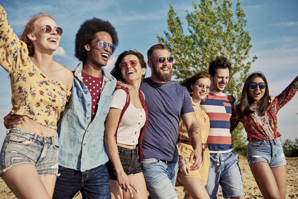 Молодые улыбающиеся люди в ряд на свежем воздухе
  - Фото, изображение