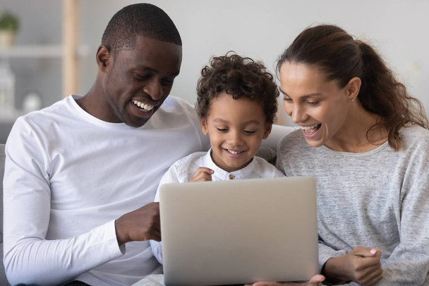 Happy mixed race family with little son enjoy using laptop - Photo, image