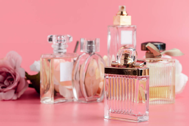 Perfume bottle with roses on pink fabric background  - 写真・画像