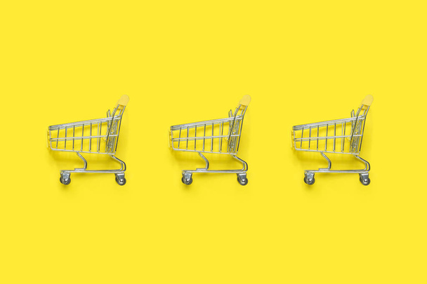 Trois chariots sur fond jaune. Concept de shopping, remise, vente. Couché plat, vue du dessus
 - Photo, image