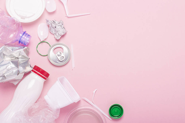 Szemétgyűjtés, műanyag és fém, rózsaszín alapon. Concept stop műanyag, újrahasznosítás, külön gyűjtése a szemetet. Lapos feküdt, felülnézet - Fotó, kép
