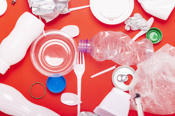 Plastic and tin waste collection on a red background. Concept stop plastic, recycling, separate collection of garbage. Flat lay, top view - Photo, Image