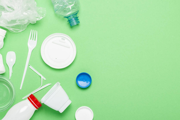 Garbage collection, plastic on a green background. Concept stop plastic, recycling, separate collection of garbage. Flat lay, top view - 写真・画像