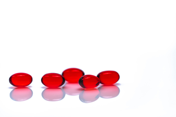 白い背景に分離された赤い柔らかいゲルカプセルの丸薬。赤色軟ゼラチンカプセルの山。ビタミンと栄養補助食品の概念。製薬業界。薬局ドラッグストア。ヘルスケア製品. - 写真・画像