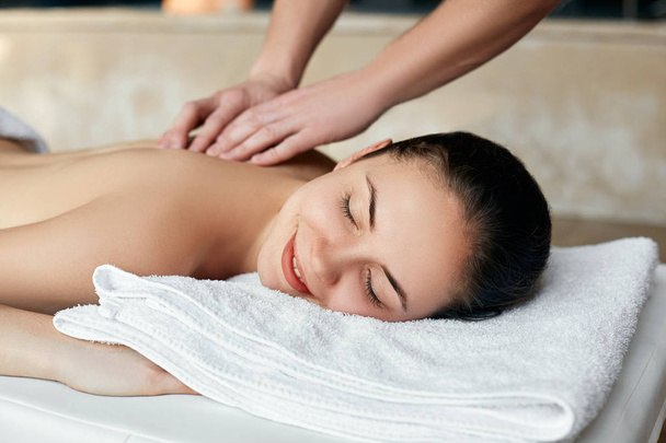 Jovem que gosta de massagem no salão de spa. Cuidado com o corpo. Mulher fazendo massagem no salão de spa
 - Foto, Imagem