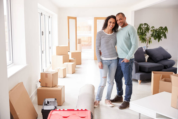 Portrait Of Loving Couple Surrounded By Boxes In New Home On Moving Day - Foto, Bild