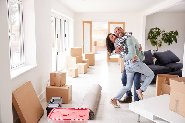Loving Couple Surrounded By Boxes In New Home On Moving Day - Foto, imagen