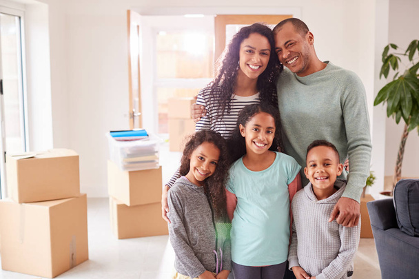 Portrait Of Family Surrounded By Boxes Standing In Room On Moving Day - Foto, afbeelding