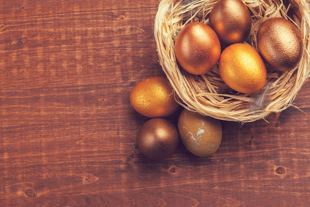 Gold Easter eggs on wooden background - Fotó, kép