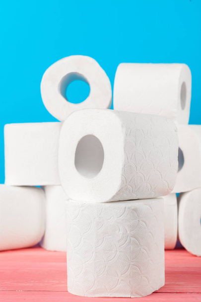 Toilet paper rolls stacked against blue background - Foto, afbeelding