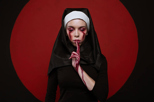 Сатанинская монахиня со шрамом на лице. Концепция Хэллоуина ужасов. Сестра молится с закрытыми глазами
 - Фото, изображение