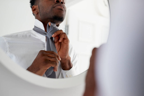 Businessman At Home Tying Necktie In Mirror Before Leaving For Work - Zdjęcie, obraz