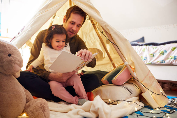 Single Father Reading With Daughter In Den In Bedroom At Home - Valokuva, kuva