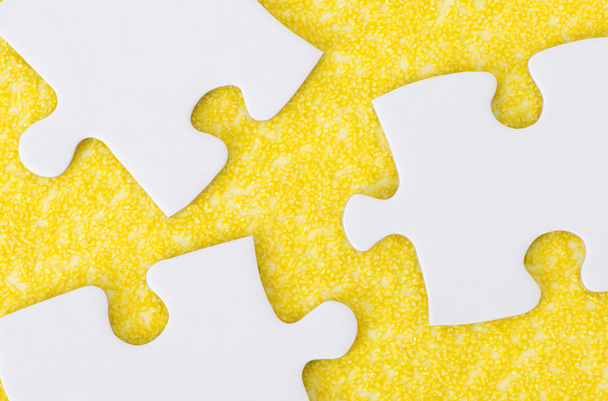 weiße Puzzleteile auf gelb strukturierter Oberfläche - Foto, Bild
