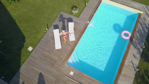 AERIAL: Mujer acostada junto a la piscina se enoja con el dron de espionaje y trata de estrellarlo. vecino molesto vuela su dron para filmar a la mujer en bikini tomando el sol, que trata de derribarlo tirando cosas
. - Metraje, vídeo