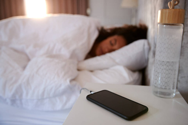 Woman Asleep In Bed With Mobile Phone On Bedside Table - Фото, зображення