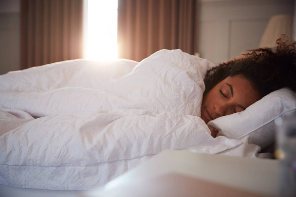 Peaceful Woman Asleep In Bed As Day Break Through Curtains - 写真・画像
