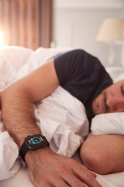 Man Asleep In Bed Wearing Smart Watch As Sun Breaks Through Curtains - Foto, afbeelding
