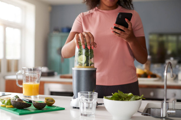 Close Up Of Woman Using Fitness Tracker To Count Calories For Post Workout Juice Drink She Is Making - Photo, Image