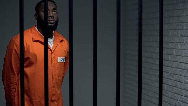 Indifferent afro american prisoner praying to god in cell, waiting for sentence - Valokuva, kuva