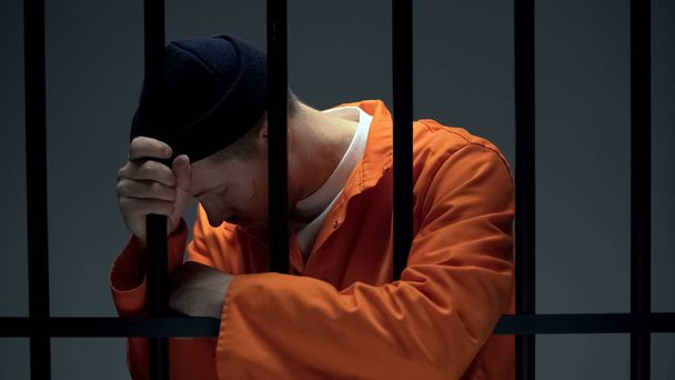 Desperate imprisoned male leaning on bars, feeling depressed, psychological help - Фото, зображення