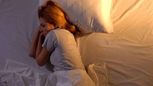 Kaukasische traurige Frau, die sich allein zu Hause im Bett aufregt und unter Depressionen leidet - Foto, Bild