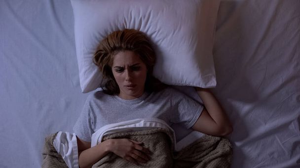 Hermostunut nainen herää sängyssä, pettynyt painajaiseen, kärsii painajaisista
 - Valokuva, kuva