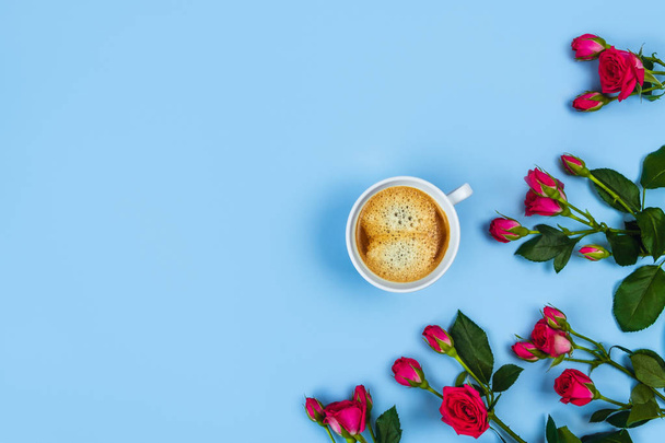 Morning Cup of coffee and a beautiful roses on blue background, top view. - Fotoğraf, Görsel