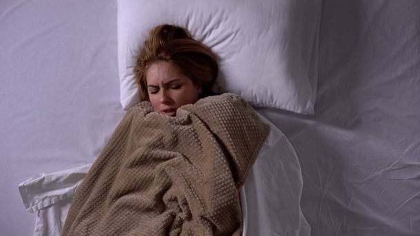 Lady covered with blanket lying in bed, feeling fever, symptoms of cold, illness - Valokuva, kuva