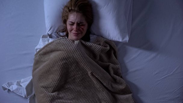 Wounded female victim crying in bed, domestic violence, trauma hopelessness - Valokuva, kuva