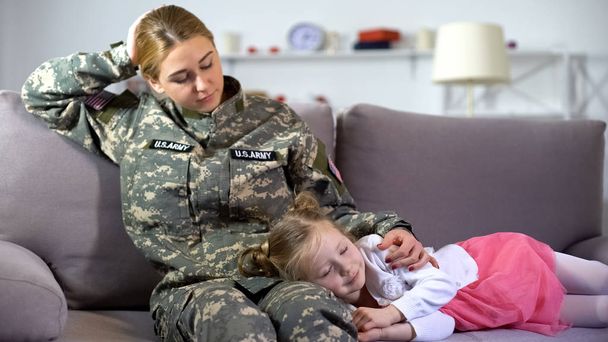 Caring american military mother stroking little kid sleeping on sofa, homecoming - Valokuva, kuva