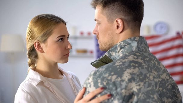 Upset girlfriend looking at boyfriend in camouflage, goodbying before duty - Photo, Image