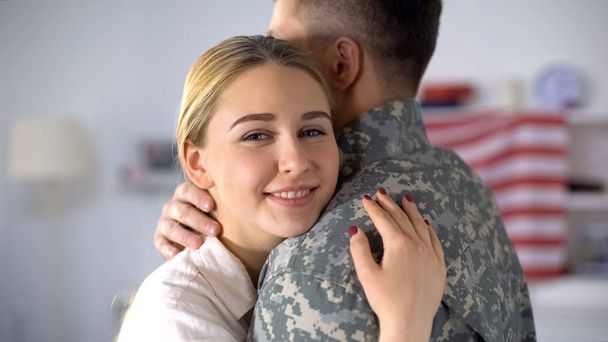 Joyful wife hugging military husband and smiling at camera, homecoming after war - Foto, Imagem