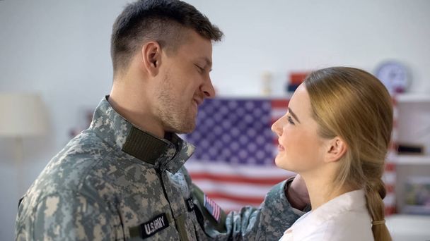 US soldier in uniform holding girlfriend face and smiling, homecoming after war - 写真・画像