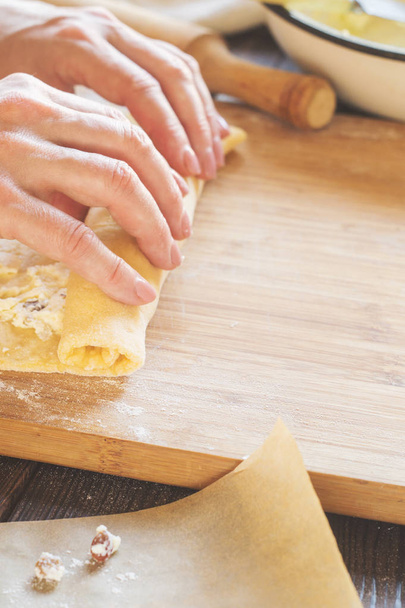 Woman is preparing a roll of dough with a curd filling - Fotó, kép