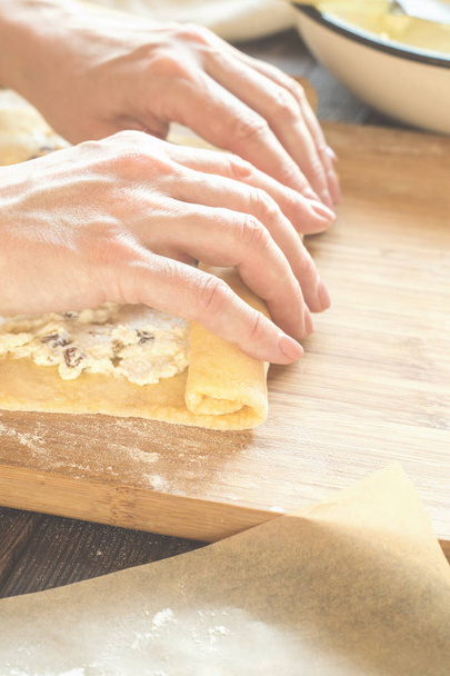 Woman is preparing a roll of dough with a curd filling - Foto, imagen