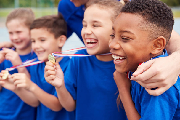 Children With Male Coach Showing Off Winners Medals On Sports Day - Photo, image
