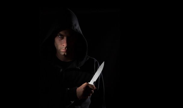Опасный человек в капюшоне держит нож
 - Фото, изображение
