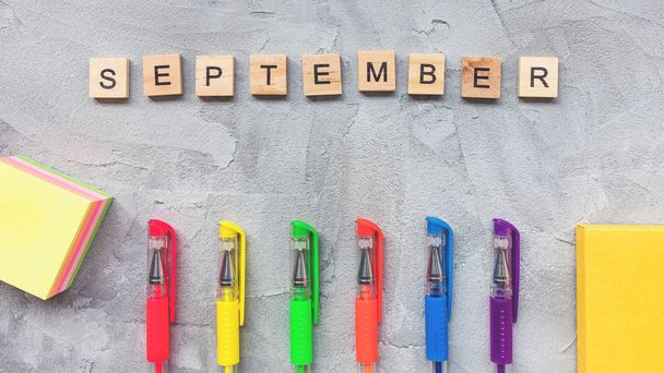 Word september en veelkleurige gel pennen op een grijze achtergrond. - Foto, afbeelding