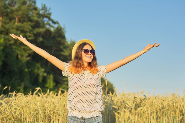 Girl teenager in hat in wheat field with open hands - Foto, afbeelding