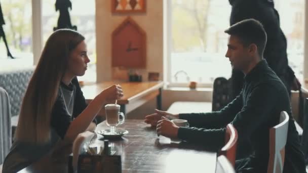 Junge und Mädchen plaudern im Café und trinken Kaffee - Filmmaterial, Video