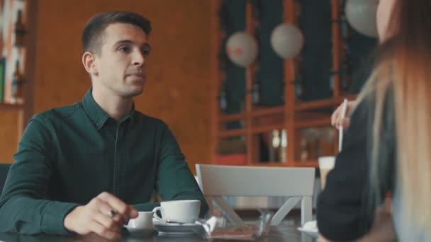 Dziewczyna i mężczyzna rozmawiają w miejskiej kawiarni - Materiał filmowy, wideo