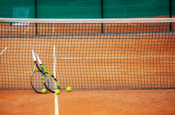 Tennis rackets en ballen die tegen het net sprongen. - Foto, afbeelding