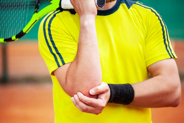 Male tennis player holding his injured elbow.  - Foto, Imagen
