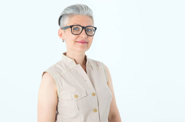 Portrait of a beautiful mature woman in glasses on a light background. - Фото, изображение