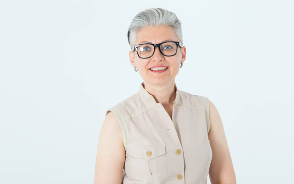 Portrait of a beautiful mature woman in glasses on a light background. - Фото, зображення